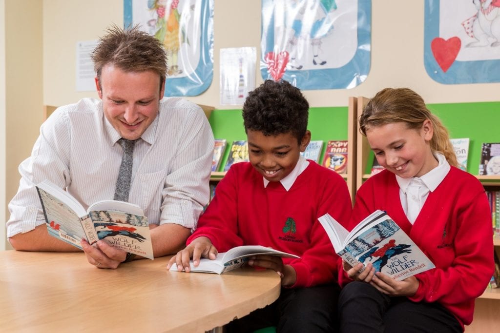 Teacher and two pupils reading books